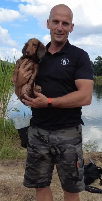 Man holding a small dog outdoors.